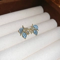 Makro-Detail von Blatt-Ohrringen mit blauem Emaille und weißem Zirkon in Gold-Ausführung - Ohrstecker mit blauen Blättern und Silbernadel