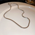 Macro shot of silver snake bone chain necklace with high-shine polished metallic finish - Necklace - Silver