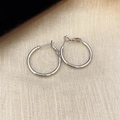 Minimalist silver hoop earrings with polished metal finish on beige textured background - 2.5cm / Silver