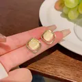 Elegant gold square stud earrings featuring yellow cat-eye stone inserts on fingertips - Gold Rounded Square Yellow Opal Stud Earrings