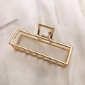 Detail of a large gold metal hair claw clip with rectangular hollow design on satin fabric - KC Gold-Rectangular