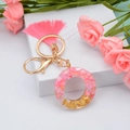 Pink resin alphabet keychain with gold leaf, pink tassel and shell flakes on white stand - Letter O