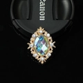 Macro shot of oval vintage alloy brooch with colorful gemstone and white rhinestones - AB Color