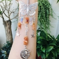 Detailed close-up of butterfly suncatcher with crystal beads and metal celestial charms - Red Aventurine