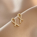 Detailed view of golden ribbon earrings with inlaid rhinestones on beige silk fabric - 7# Fish Tail Studs