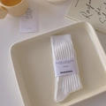 White crew socks with vertical rib knit texture and minimalist paper packaging wrap - White