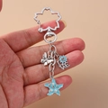 Portachiavi in argento con fiore smaltato blu, farfalla e ciondolo LOVE - Stella marina