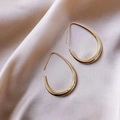 Close-up of golden teardrop geometric earrings on elegant silk background - Gold Teardrop Hook