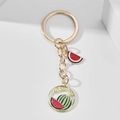 Detaillierte Makroansicht eines goldenen Schlüsselanhängers mit rotem Wassermelonen-Emaille - Wassermelone