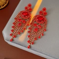Dettaglio degli orecchini vintage a nappa rossi con strass su velluto grigio - Rosso