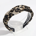 Close-up of leopard print braided headband on a clear acrylic stand with soft lighting - Beige Leopard