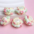 Detailed macro view of five cream resin beads with pink floral patterns for DIY jewelry - White Bead Yellow Cream Green Heart Flower