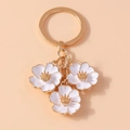 Détail d'un porte-clés fleur de cerisier blanc avec bordures et maillons en métal doré - Blanc