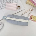 Detail of light blue quilted down-style pencil case with white zipper and grey handle strap - Light Blue