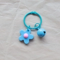 Blue knit-style flower charm with a matching bell and metal ring on light paper - Light Blue