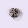 Heart-shaped natural dalmatian jasper gemstone with black spots on a purple background - Spotted Stone
