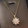 Close-up of golden sunflower pendant necklace with marquise white crystals on brown base - Gold - Spinning Eight-Petal Flower