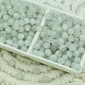 Detailed view of 6mm light green cracked glass beads in a white ceramic dish - Jade Texture Single Grey (6mm)