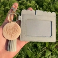 Close-up of light gray faux leather card holder with tassel and engraved I love you charm - Gray