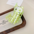 Macro view of neon yellow translucent acrylic cat skull hair claw clip on wooden tray - 7.8cm / Green