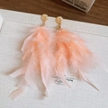 Detalle de pendientes largos de plumas melocotón con tachuelas de metal dorado bohemio - Rosa