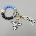 Detail of blue and cow print silicone bead bracelet with Mama cow head charm and tassel - Dark Blue