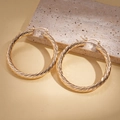 Dettaglio della texture a spirale geometrica dorata su grandi orecchini a cerchio - Oro