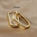 Close-up of 23mm gold-plated U-shaped minimalist hoop earrings on champagne silk fabric - Gold / 23mm