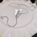 Detailansicht des silbernen Schmetterlingsanhängers mit Schlangenkette auf Keramik - Silberne Schmetterlings-Choker-Halskette