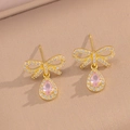 Detail van gouden strik oorbellen met roze druppelstenen en fonkelende zirkonia accenten - Gouden Roze Zirkoon Studs