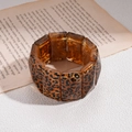 Detailopname van amberkleurige luipaardprint hars armband op decoratief vintage papier - Armband - Donkere Koffie