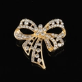 Broche nœud élégante en métal doré avec strass scintillants sur fond noir réfléchissant - Style B216