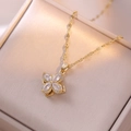Detail of a rotating golden four-leaf clover necklace with zircons in a beige jewelry box - Clover Necklace / Gold