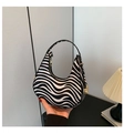Close-up of zebra pattern crescent bag with metal zipper and buckle held by hand - Zebra Print