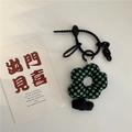Detail of floral bag charm with green checkerboard pattern and creative black chain - Green & Black Checkerboard Flower