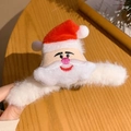 Close-up of a plush Santa Claus hair claw clip with embroidered details and soft red fur - Santa Claus