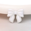 Macro view of a white bow accessory with neat rows of inlaid pearls for DIY crafts - White