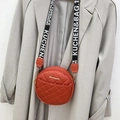 Fashionable round quilted crossbody bag in vibrant orange red with wide logo strap - Red