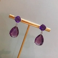 Macro view of purple pear-cut gemstone drop earrings with silver metal mountings - Purple