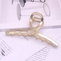 Macro shot of large golden metal claw clip with a polished finish on a book background - Gold Metal