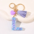 Detailed close-up of purple heart tassel keychain with resin letter L and gold clasp - Letter L