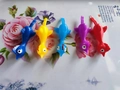 Five colorful slingshot rubber chickens in blue yellow purple and red on a white tray - Mixed Color Slingshot Turkey