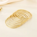 Macro-opname van negen minimalistische 3mm gouden roestvrijstalen stapelbare armbanden - 46mm Binnendiameter / 18K Vergulde Zware Stapelstijl