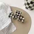 Macro view of checkered claw clip with unique wavy shape on leather display tray - M-shaped Claw