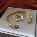 Conjunto de brazalete y anillo dorado con piedras de circonita sobre seda roja elegante - Conjunto De Dos Piezas De Brazalete Y Anillo