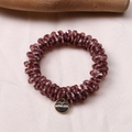 Macro detail of deep purple multifaceted crystal beads and golden Morava metal charm - Red