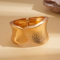 Detailed view of golden wide open cuff bracelet with hammered metal texture and glossy finish - Gold