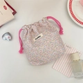 Close-up of floral drawstring storage bag with pink cords and woven brand label - Floral