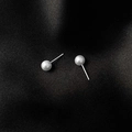 Vue macro de boucles d'oreilles perles blanches minimalistes sur fond de soie noire - Tige en Argent S925-6mm