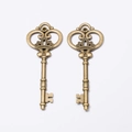 Paire de pendentifs clés couronne vintage en alliage de bronze sur fond blanc - Bronze Antique